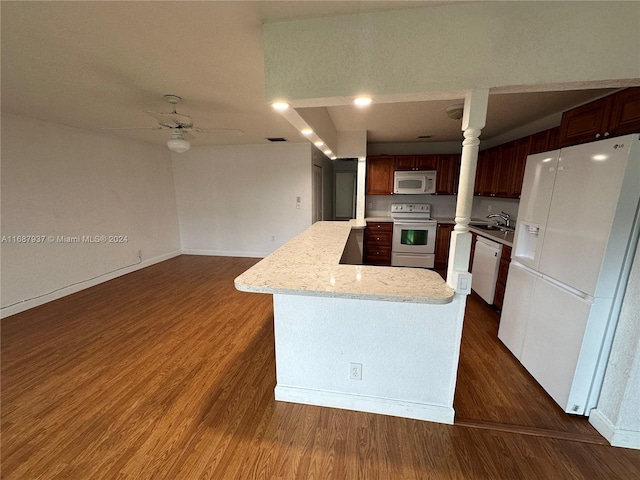 kitchen with dark wood-type flooring, white appliances, sink, and a kitchen island