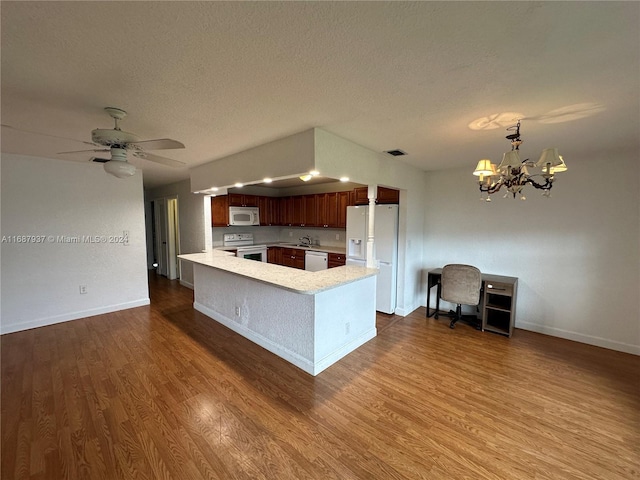 kitchen featuring kitchen peninsula, ceiling fan with notable chandelier, a textured ceiling, hardwood / wood-style floors, and white appliances