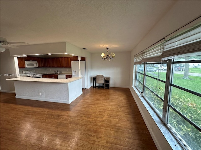 kitchen featuring a textured ceiling, kitchen peninsula, dark hardwood / wood-style floors, and white appliances