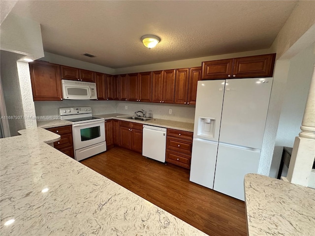 kitchen featuring light stone counters, a textured ceiling, sink, dark wood-type flooring, and white appliances