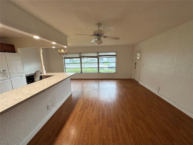 unfurnished living room with a textured ceiling, dark hardwood / wood-style floors, and ceiling fan with notable chandelier