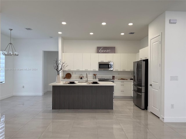 kitchen featuring a kitchen island with sink, appliances with stainless steel finishes, decorative light fixtures, and white cabinets