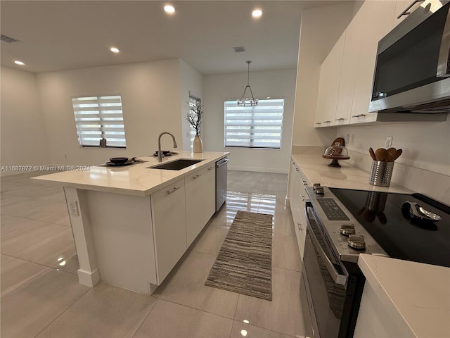 kitchen featuring white cabinetry, a center island with sink, stainless steel appliances, and sink