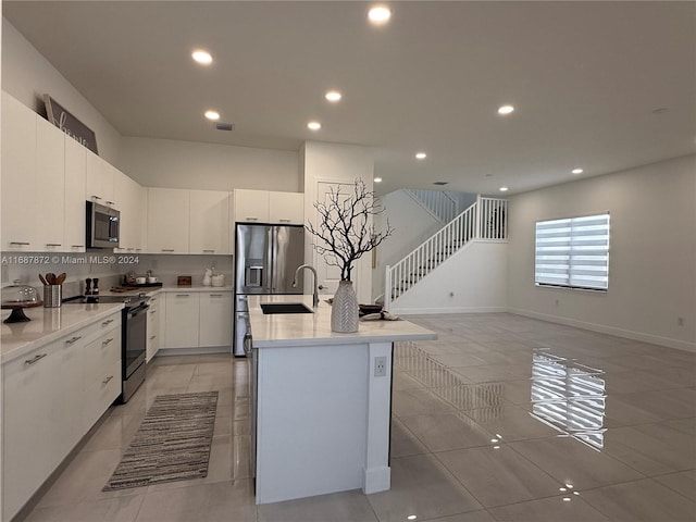 kitchen featuring white cabinetry, a kitchen island with sink, stainless steel appliances, and tasteful backsplash