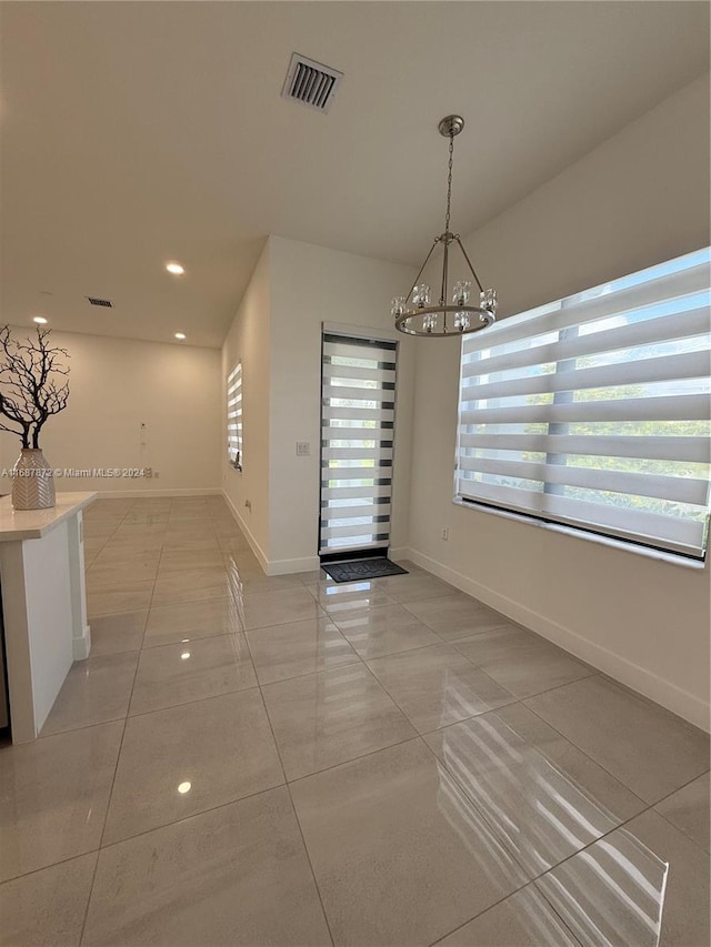 unfurnished dining area featuring a chandelier, plenty of natural light, and light tile patterned floors