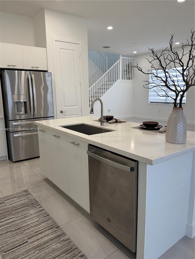 kitchen featuring sink, appliances with stainless steel finishes, white cabinetry, and an island with sink