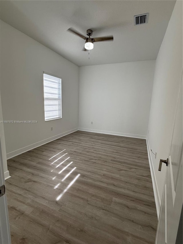 empty room featuring dark wood-type flooring and ceiling fan