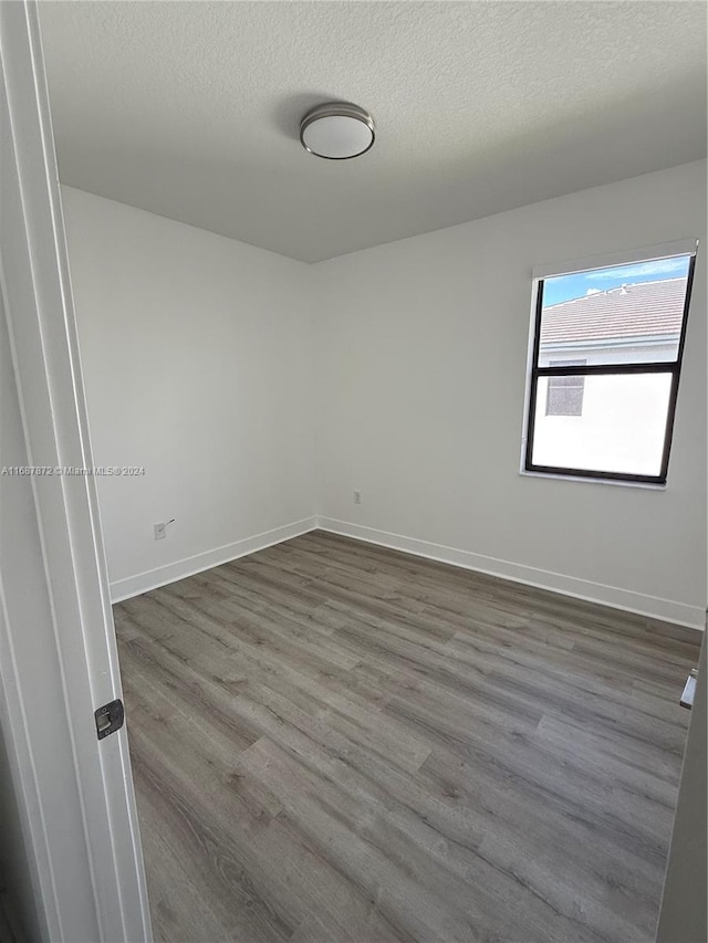 empty room with a textured ceiling and dark hardwood / wood-style flooring