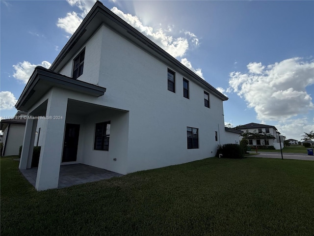 view of side of home with a patio and a lawn