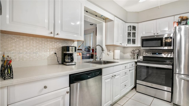 kitchen with stainless steel appliances, backsplash, sink, light tile patterned floors, and white cabinets