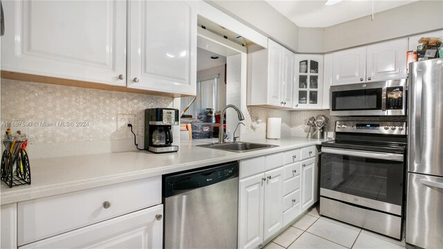 9404 NW 70th Pl, Tamarac, FL 33321 - kitchen featuring appliances with stainless steel finishes, a sink, light tile patterned floors, and white cabinetry
