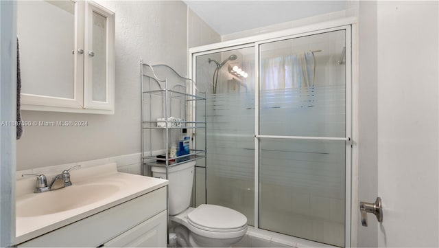 bathroom featuring vanity, an enclosed shower, and toilet