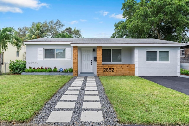 view of front facade featuring aphalt driveway, a front lawn, and stucco siding