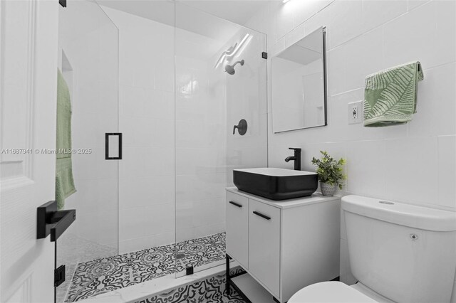 bathroom with vanity, toilet, an enclosed shower, and tile walls