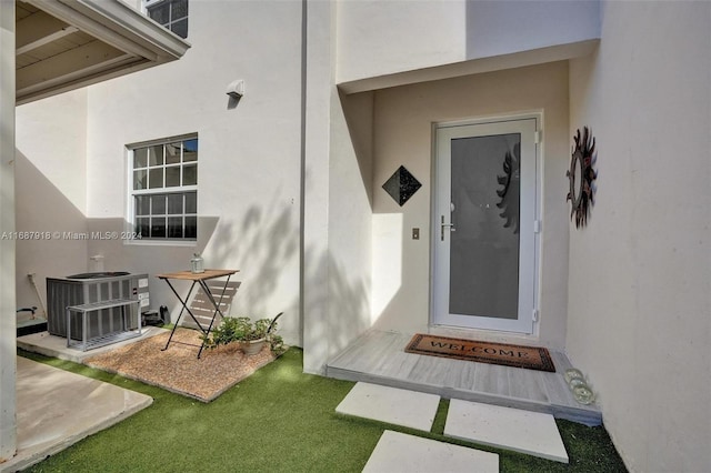 property entrance featuring a lawn and central AC unit