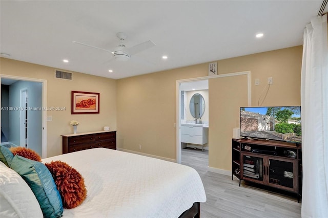 bedroom featuring light hardwood / wood-style floors, ceiling fan, and ensuite bath