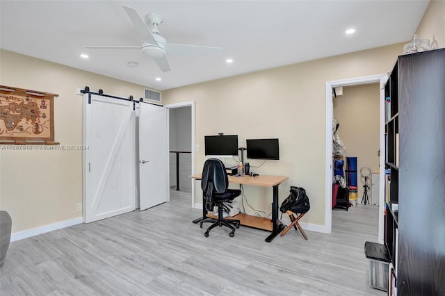 home office with light hardwood / wood-style floors, a barn door, and ceiling fan