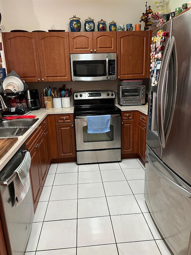 kitchen featuring stainless steel appliances, sink, and light tile patterned floors