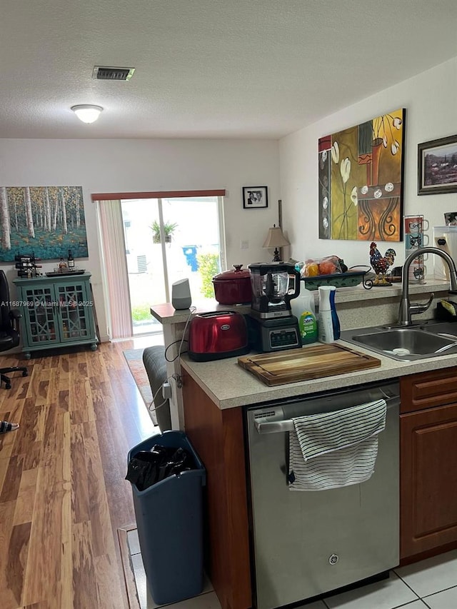 kitchen with dark brown cabinetry, sink, a textured ceiling, light hardwood / wood-style flooring, and dishwasher