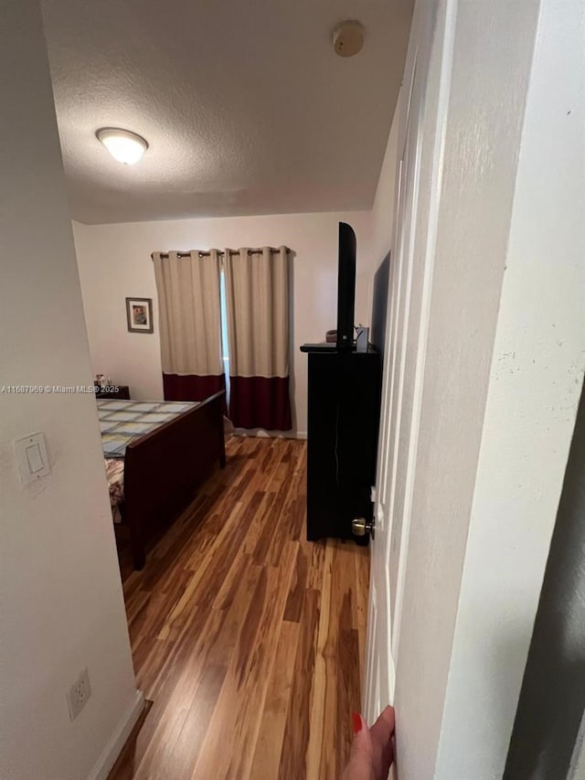 corridor with dark hardwood / wood-style flooring and a textured ceiling