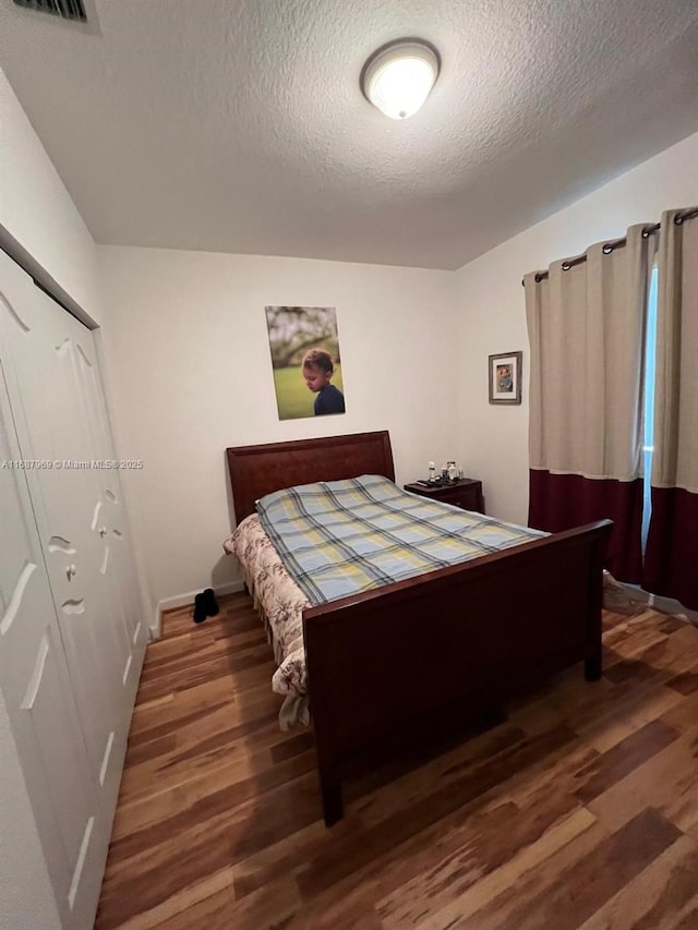 bedroom featuring dark wood-type flooring, a textured ceiling, and a closet