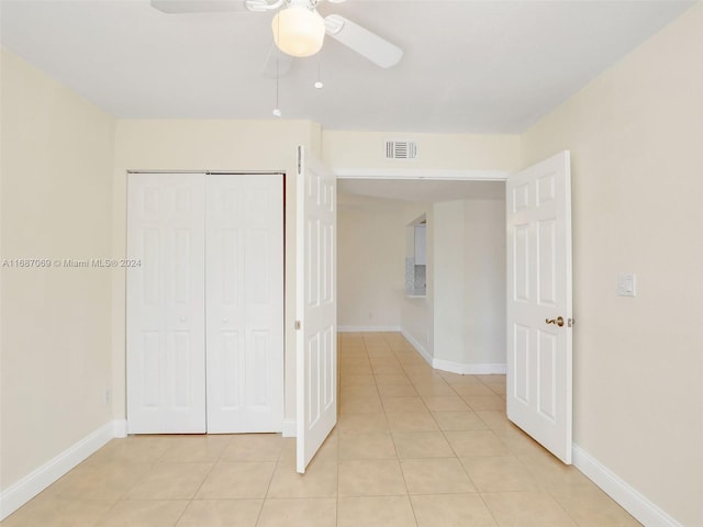 unfurnished bedroom with light tile patterned flooring, ceiling fan, and a closet