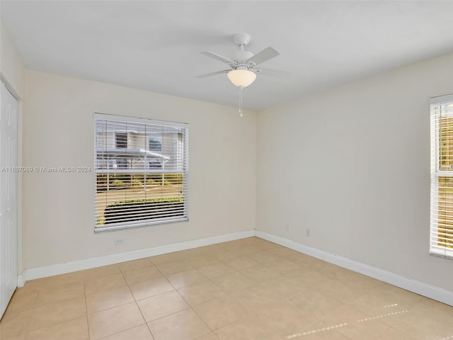 empty room with plenty of natural light, ceiling fan, and light tile patterned flooring