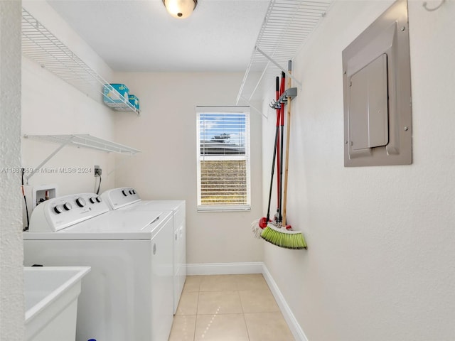 clothes washing area featuring electric panel, light tile patterned flooring, sink, and washer and clothes dryer