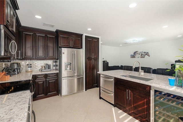 kitchen featuring sink, stainless steel appliances, wine cooler, light stone counters, and backsplash