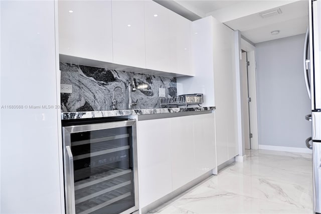 interior space featuring wine cooler, sink, tasteful backsplash, dark stone counters, and white cabinets