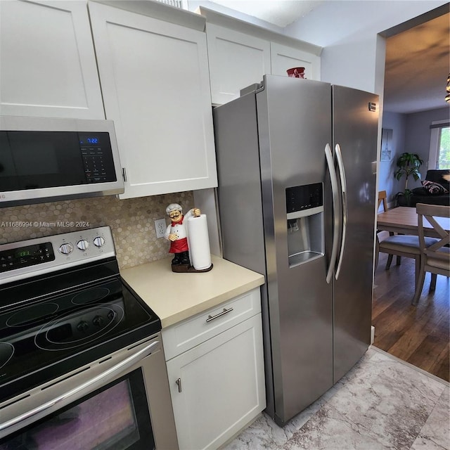 kitchen with light hardwood / wood-style flooring, backsplash, appliances with stainless steel finishes, and white cabinets