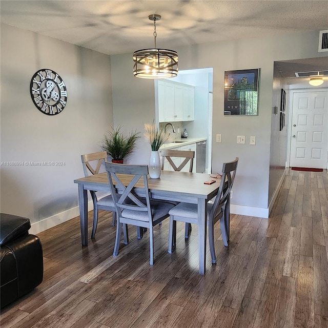 dining room featuring dark hardwood / wood-style floors, a textured ceiling, a chandelier, and sink