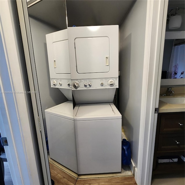 washroom featuring stacked washing maching and dryer, light hardwood / wood-style flooring, and sink