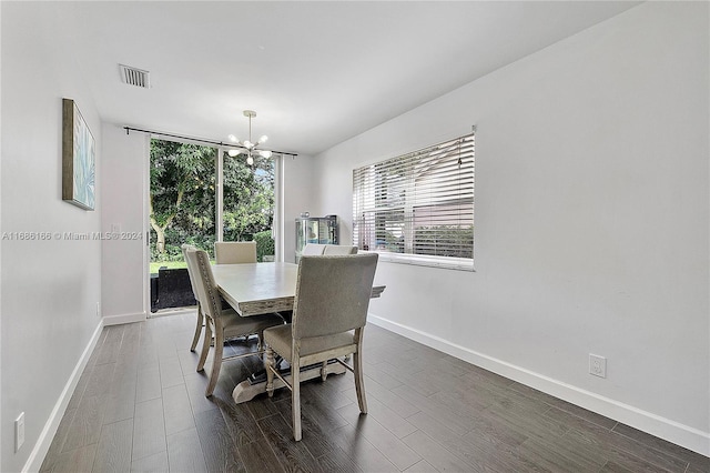 dining area featuring dark wood-type flooring and an inviting chandelier