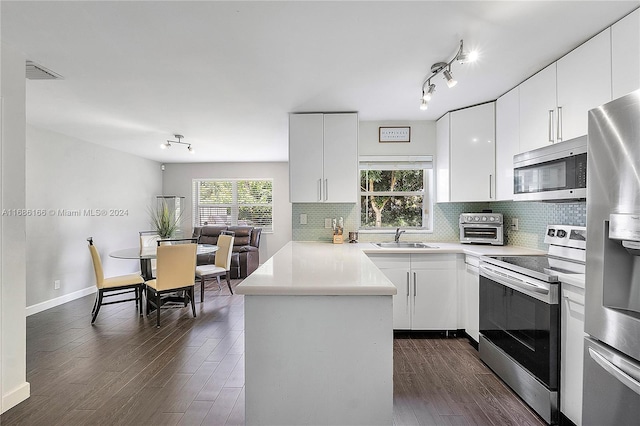 kitchen featuring white cabinetry, kitchen peninsula, appliances with stainless steel finishes, and dark hardwood / wood-style flooring