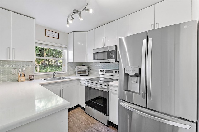 kitchen with stainless steel appliances, dark wood-type flooring, white cabinets, sink, and tasteful backsplash