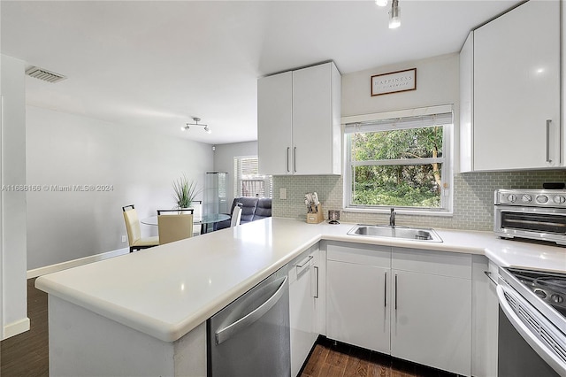 kitchen featuring stainless steel appliances, kitchen peninsula, sink, and white cabinets