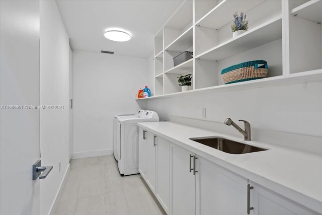 laundry room featuring washer and dryer, sink, and cabinets