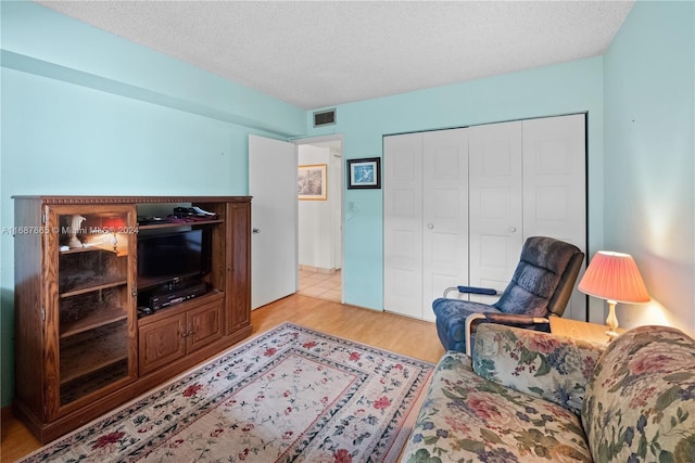 living room with a textured ceiling and light hardwood / wood-style flooring