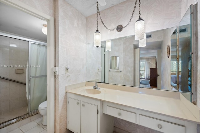 bathroom with a shower with door, vanity, a textured ceiling, tile patterned flooring, and toilet