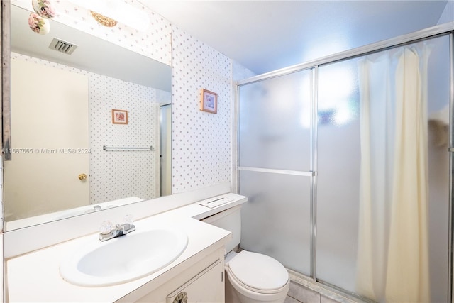 bathroom with toilet, vanity, and an enclosed shower