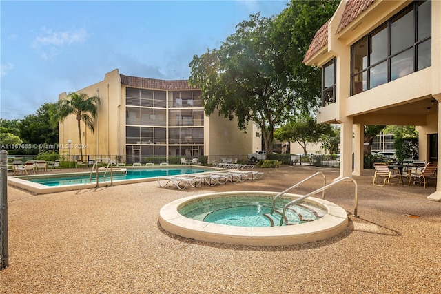 view of swimming pool featuring a community hot tub and a patio