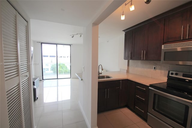 kitchen featuring stainless steel appliances, light tile patterned floors, sink, and backsplash