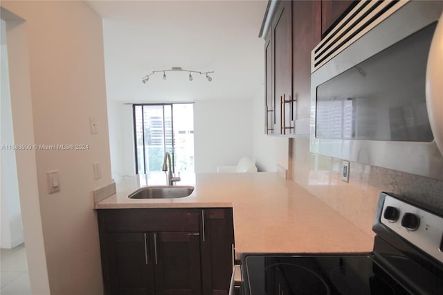 kitchen with dark brown cabinets, sink, range, and light tile patterned floors