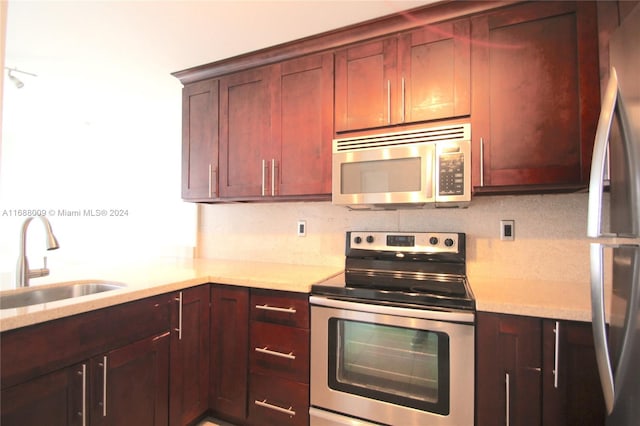 kitchen with decorative backsplash, appliances with stainless steel finishes, sink, and light stone counters