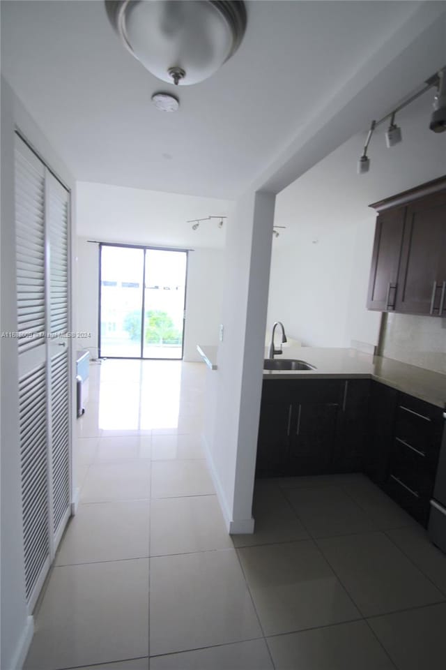 kitchen featuring dark brown cabinets, sink, and light tile patterned flooring