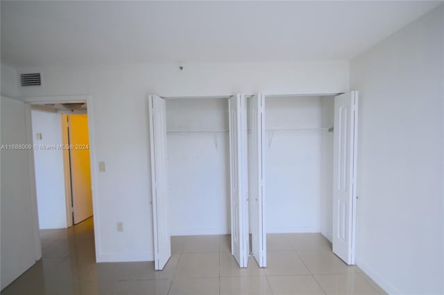 unfurnished bedroom featuring light tile patterned flooring and multiple closets