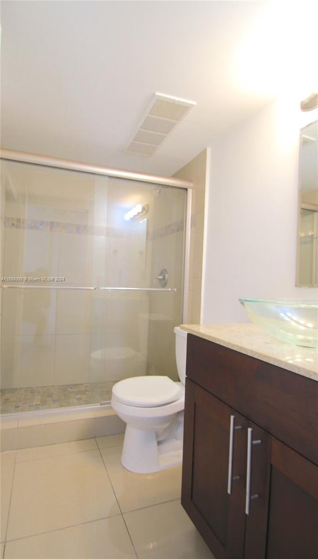 bathroom featuring vanity, tile patterned floors, toilet, and a shower with shower door