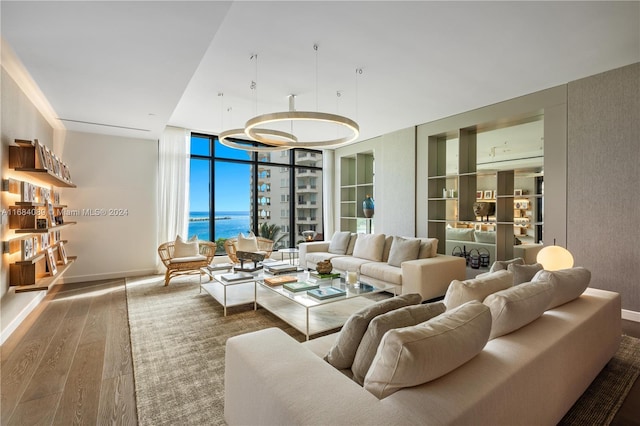 living room with hardwood / wood-style floors, a wall of windows, and a water view