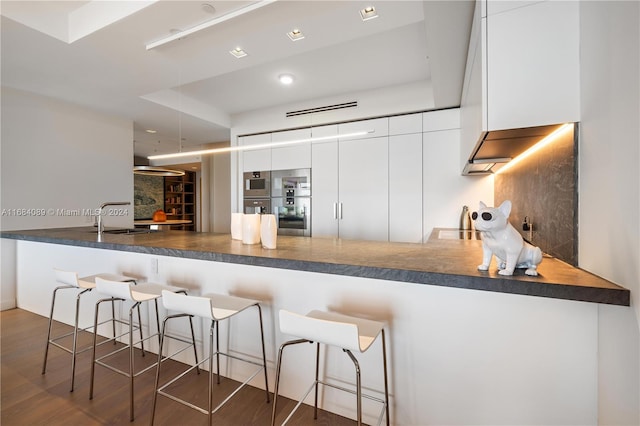 kitchen featuring kitchen peninsula, sink, dark hardwood / wood-style floors, and white cabinets